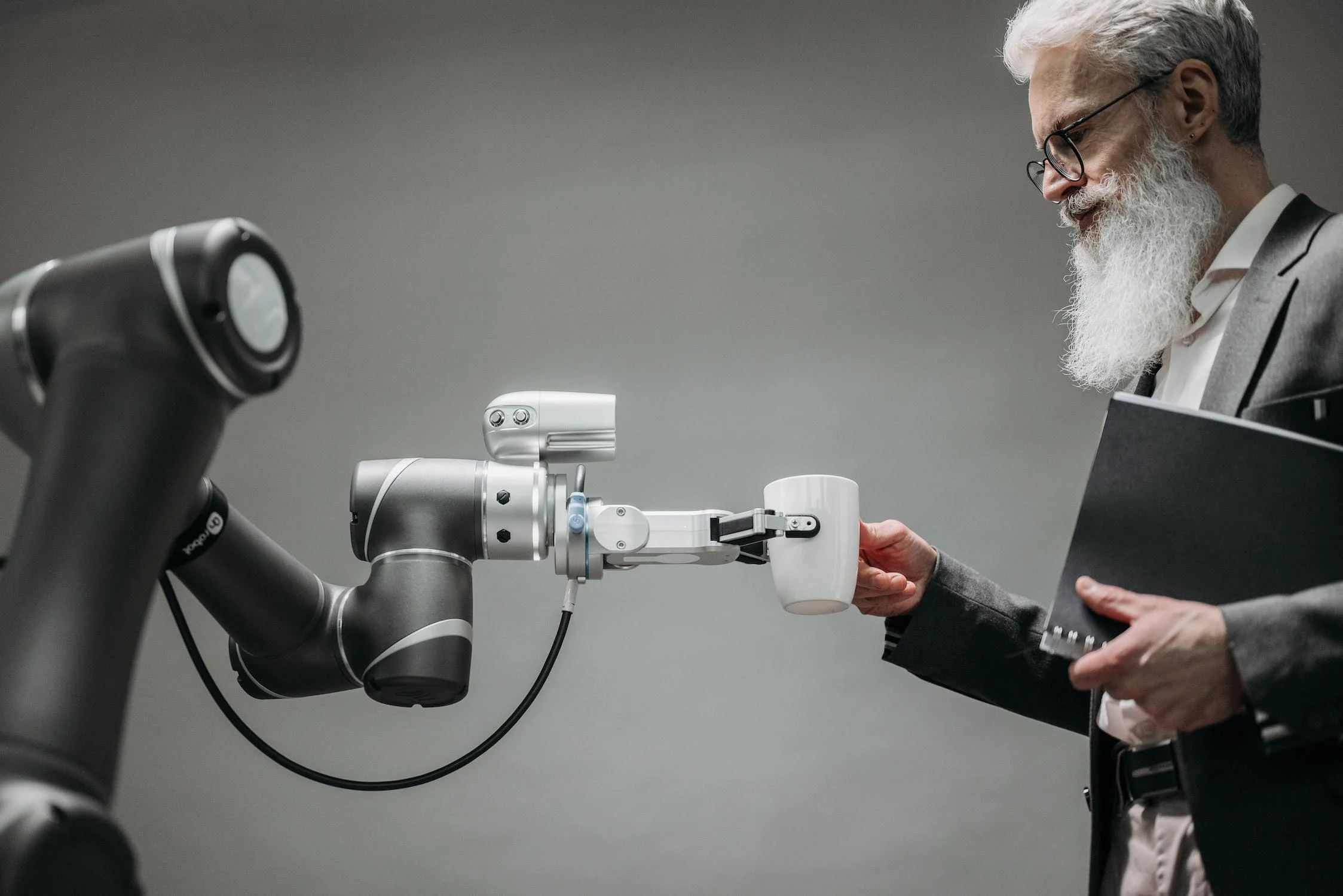 En robot hånd som holder kaffekoppen til en ansatt. Illustrasjon AI
